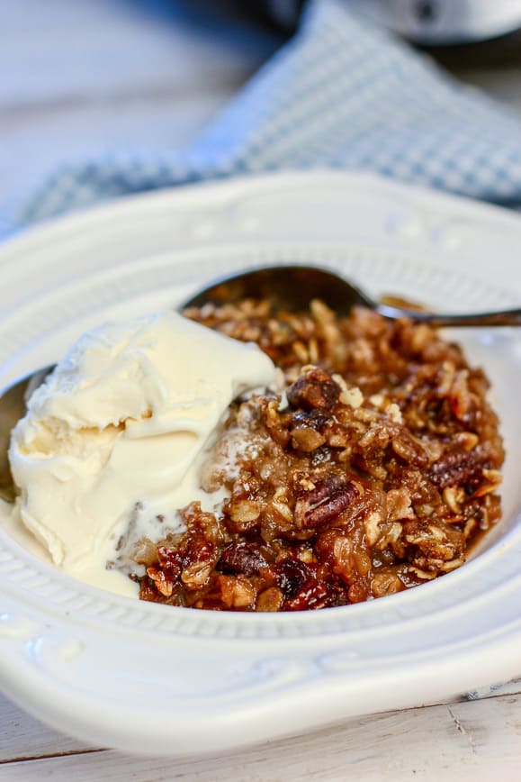 vanilla ice cream on top of apple crisp in a white bowl