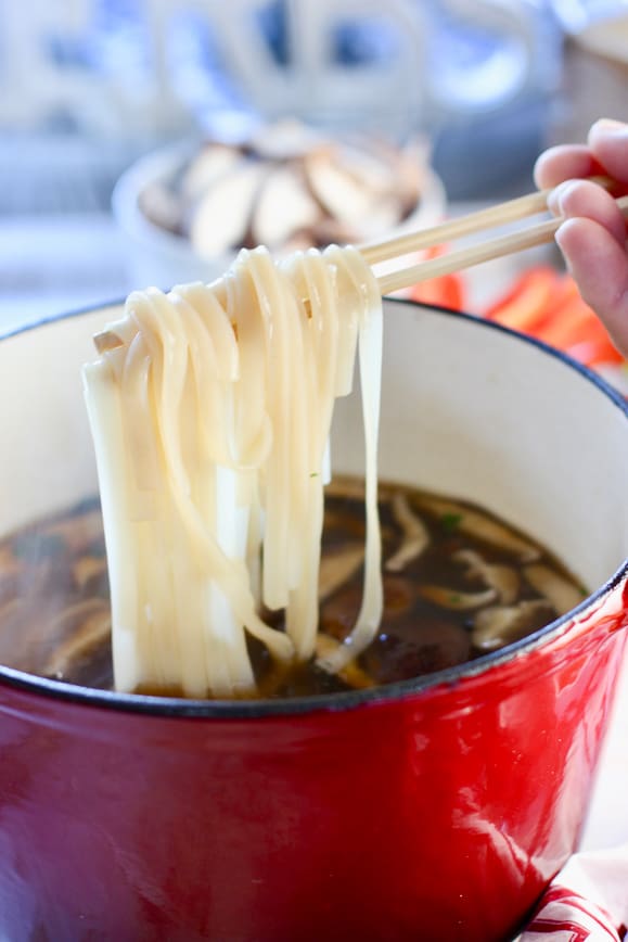 rice noodles cooking in broth for pho
