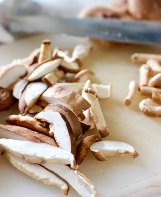 shiitake mushroom sliced on a white cutting board