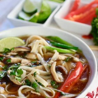 Chicken Pho on a colorful cloth with ingredients for topping