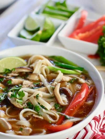 Chicken Pho on a colorful cloth with ingredients for topping