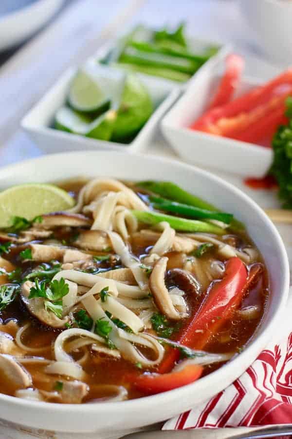 Chicken Pho on a colorful cloth with ingredients for topping