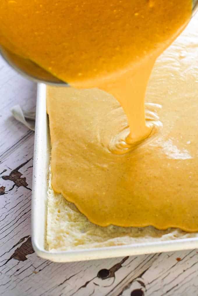 pouring pumpkin pie batter onto sheet pan with crust