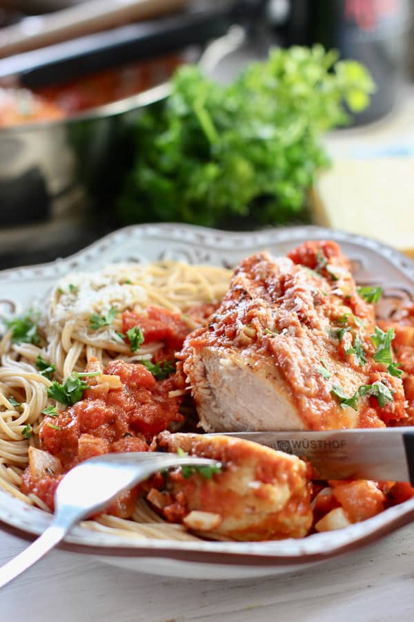 chicken with tomato sauce and spaghetti being sliced 