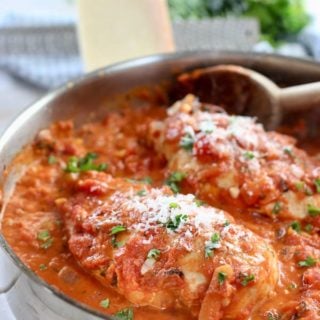 chicken breasts cooking in skillet with tomato sauce