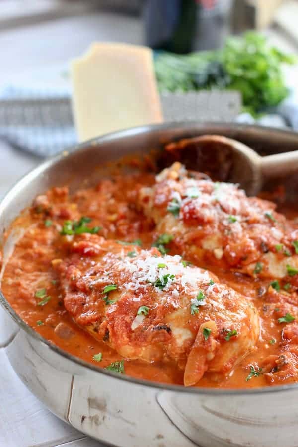 chicken breasts cooking in skillet with tomato sauce