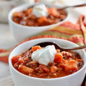 a white bowl with chili and a dollop of sour cream
