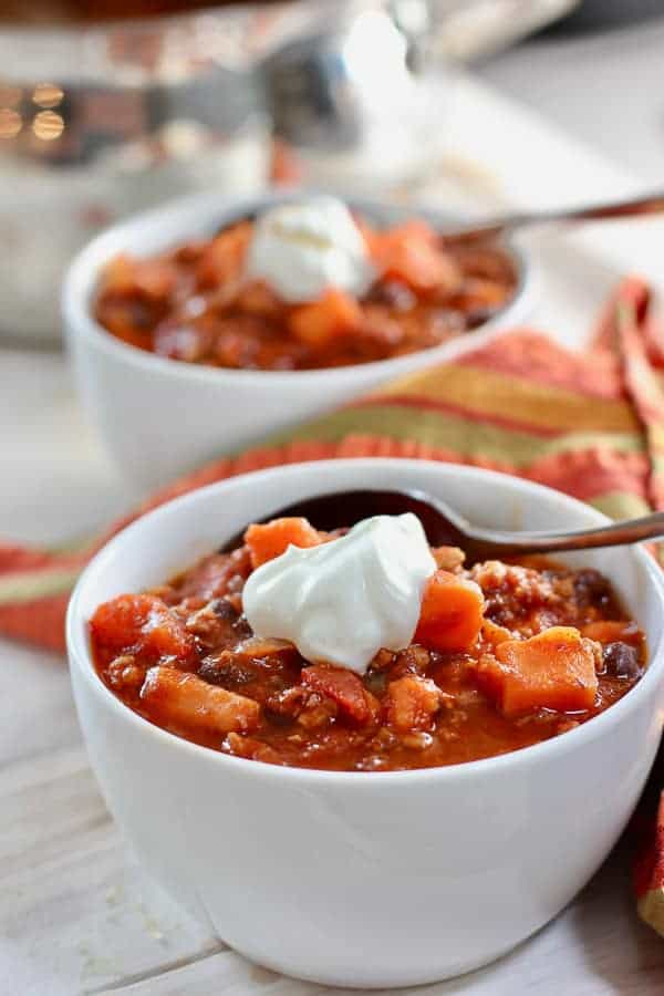 a white bowl with chili and a dollop of sour cream