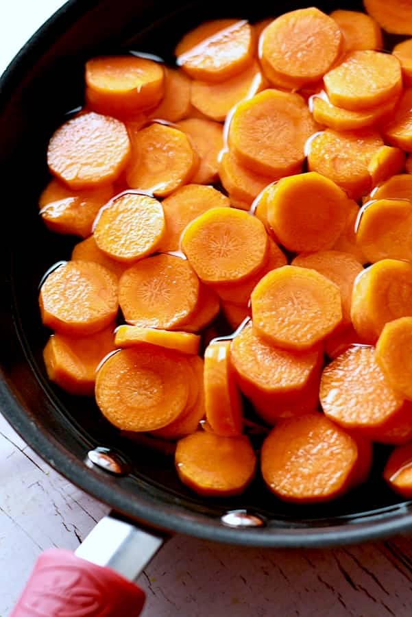 simmering carrots in a shallow pan of water