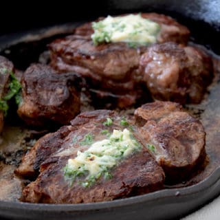 steak cooked in a cast iron pan with compound butter