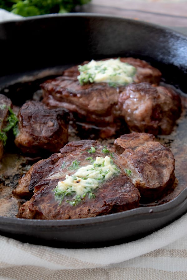 steak cooked in a cast iron pan with compound butter