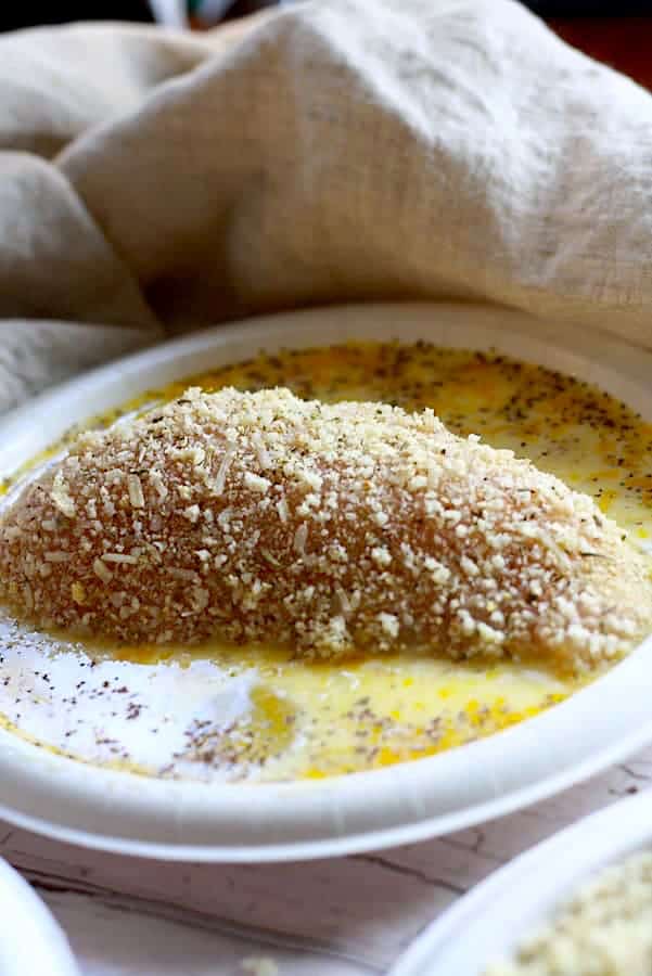 coating chicken breast in egg wash and parmesan mixture