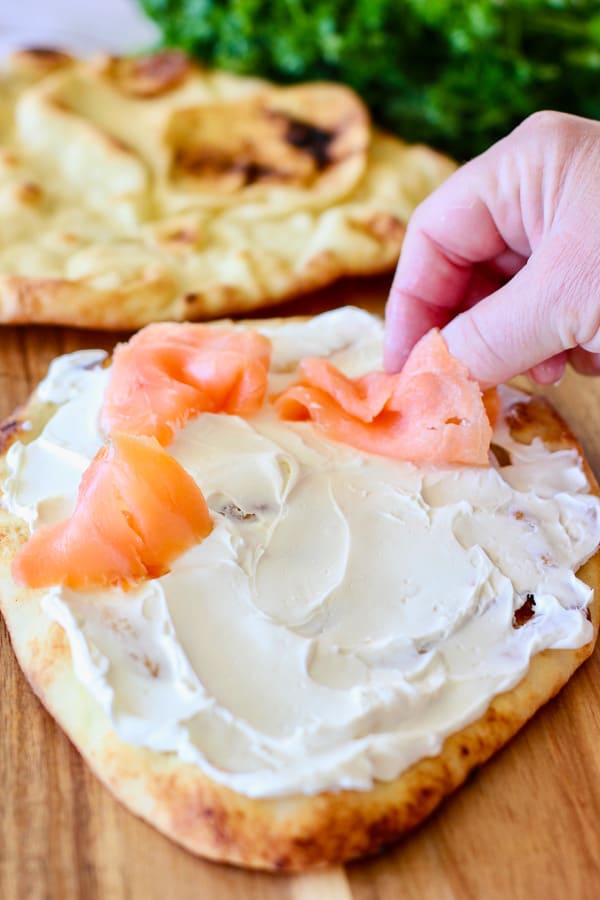 piling salmon on top of pizza