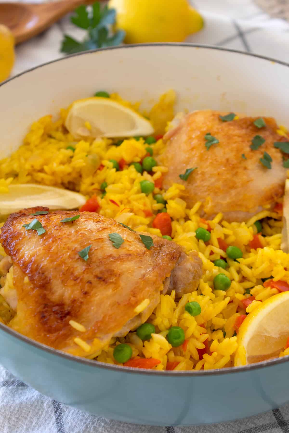 white ceramic pan full of arroz con pollo garnished with lemon wedges