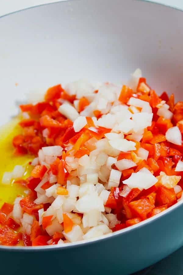 sautéing red bell pepper and onion in olive oil in pan on stove