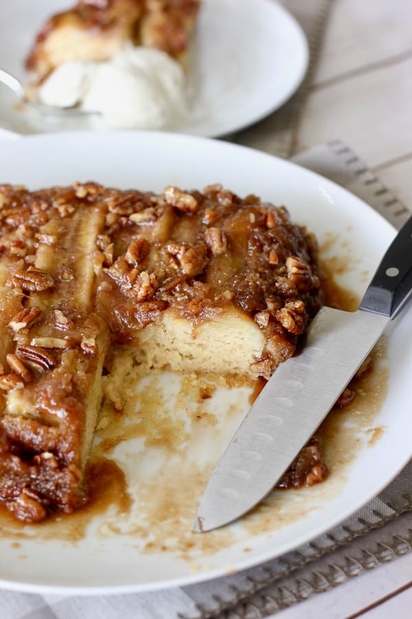 sliced banana foster cake with ice cream in the background