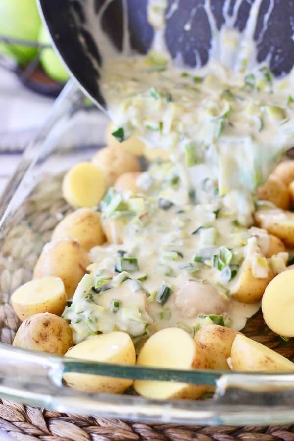 creamy leek sauce being poured over fresh potatoes