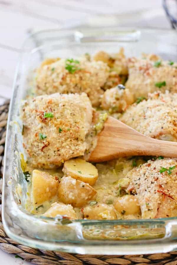 Crispy chicken thighs in a baking dish with potatoes and cream sauce