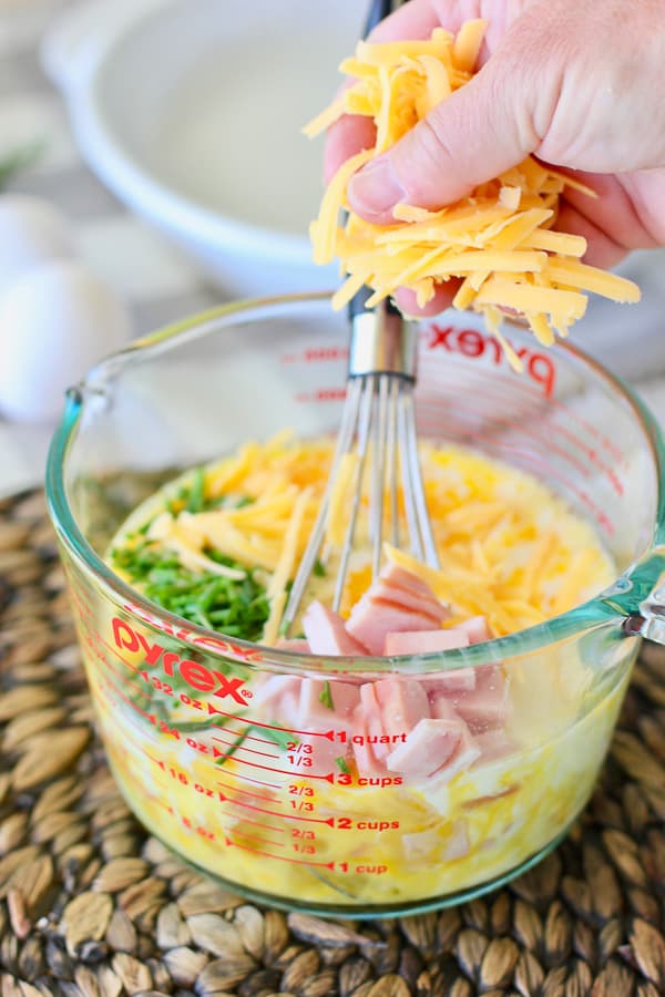 cheese being added to mixed eggs