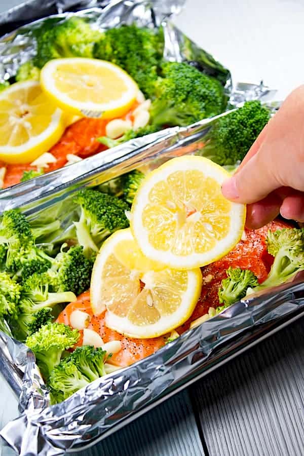 adding lemon to salmon with broccoli in foil pouch