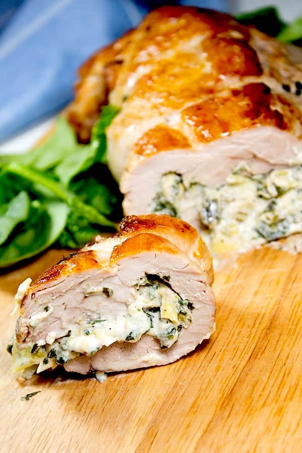 spinach artichoke stuffed pork tenderloin with slice cut on cutting board 