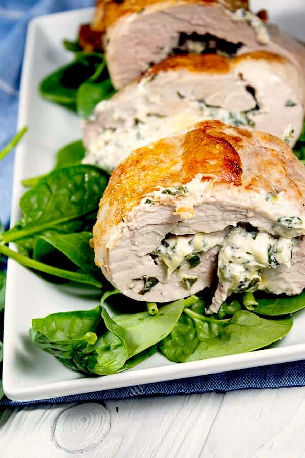 spinach stuffed pork tenderloin on platter with spinach