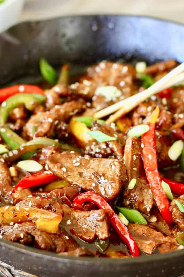 mongolian beef with peppers in skillet with chopsticks