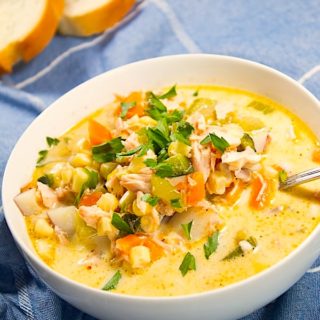 white bowl with salmon and corn chowder and sourdough bread