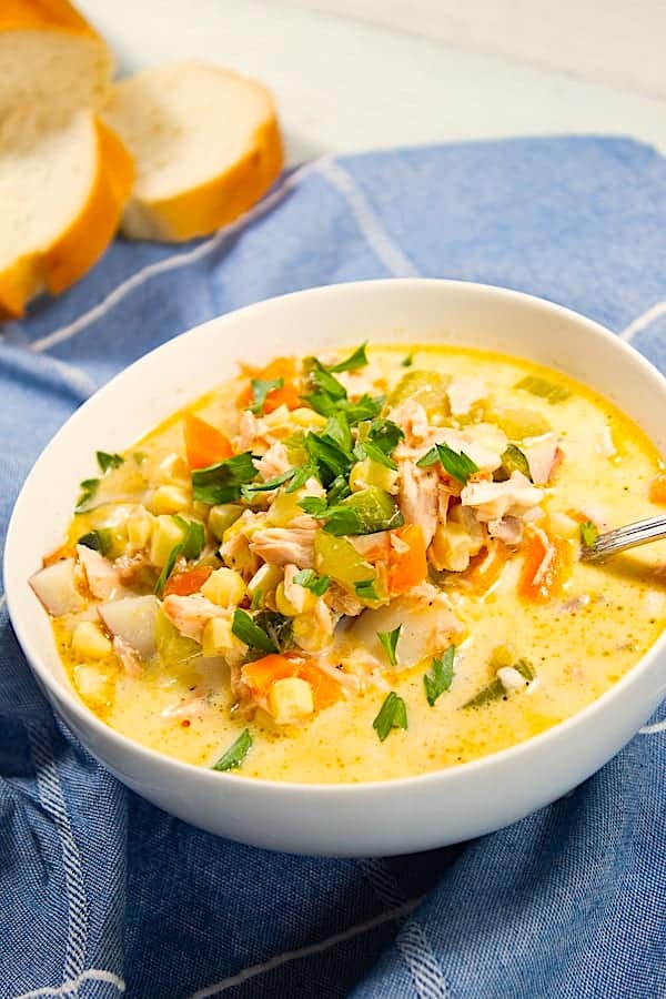 white bowl with salmon and corn chowder and sourdough bread