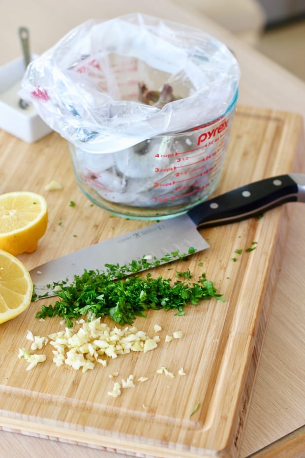 herbs and garlic being added to grilled shrimp marinade