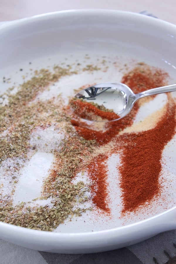 A white plate with cajun seasoning mixture on a silver spoon