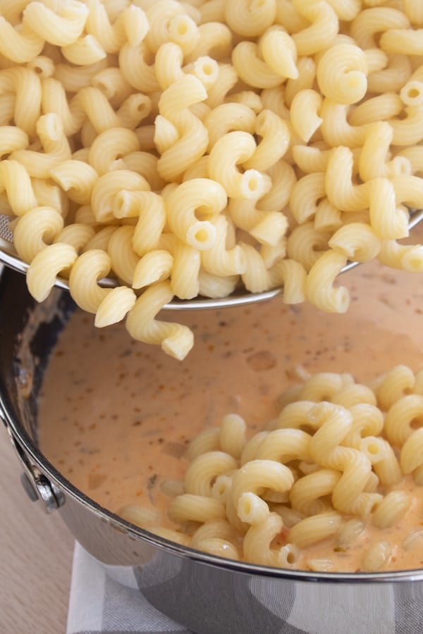 Cajun Sauce in a skillet with pasta being poured in