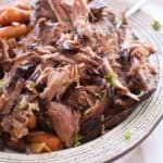 Tender slow cooker shredded pot roast on a cream colored plate