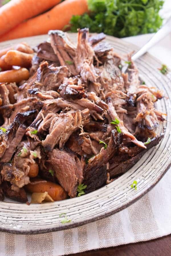 Tender slow cooker shredded pot roast on a cream colored plate