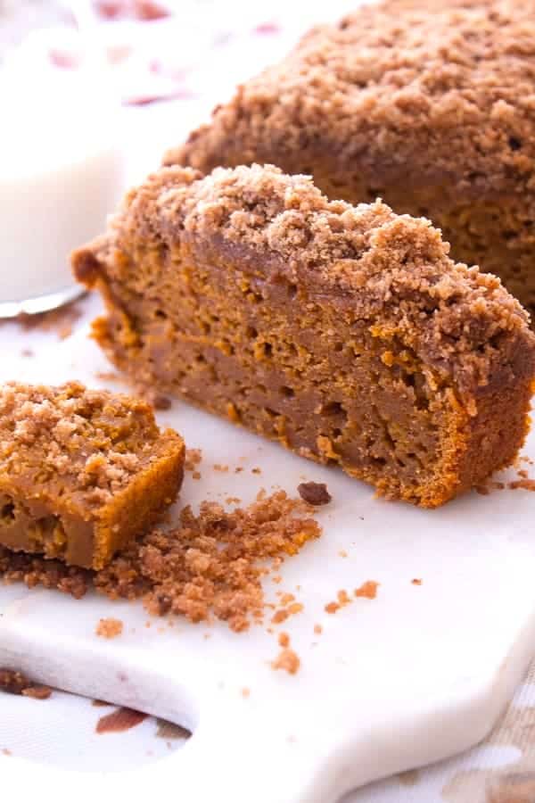 sliced pumpkin loaf cake with streusel topping on a white granite cutting board