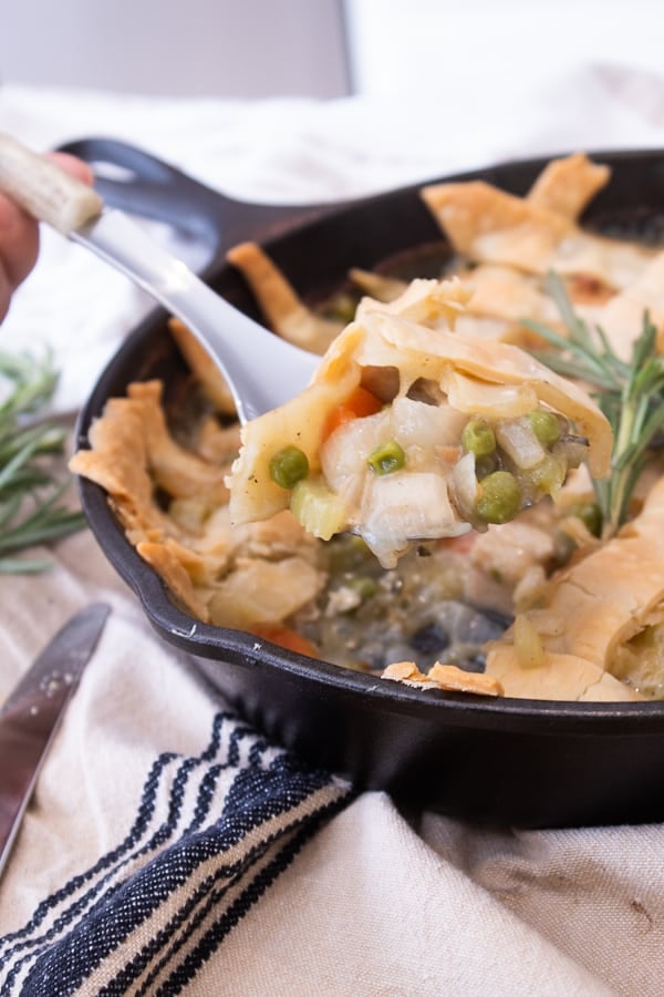 chicken pot pie in a cast iron skillet with a spoonful showcawed