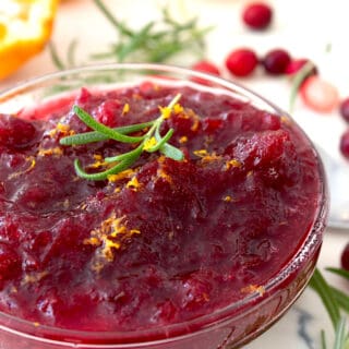 cranberry sauce in a clear bowl with rosemary garnish