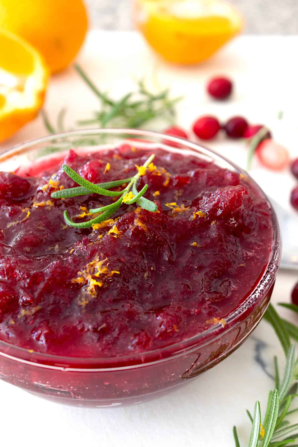 cranberry sauce in a clear bowl with rosemary garnish