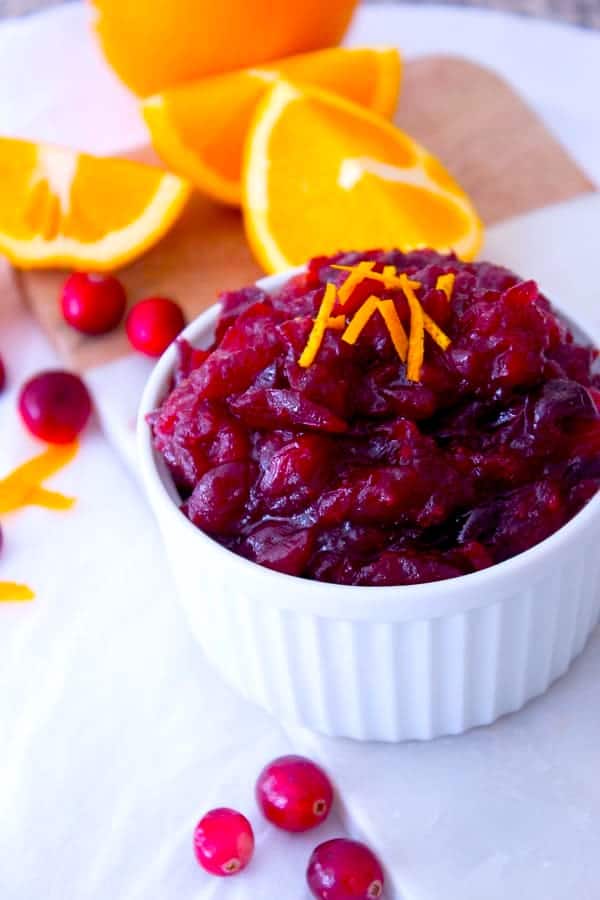 cranberry sauce in white dish with whole oranges in background