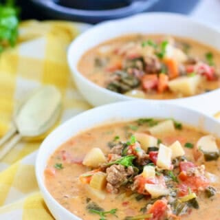 Potato sausage soup served up in a white bowl