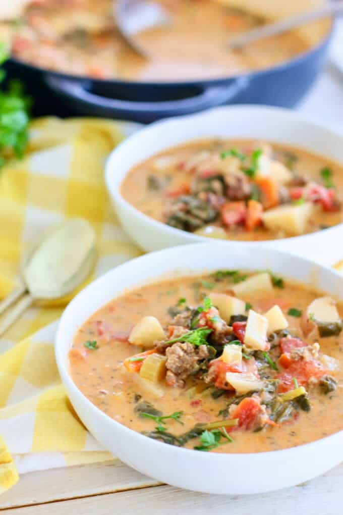 Potato sausage soup served up in a white bowl