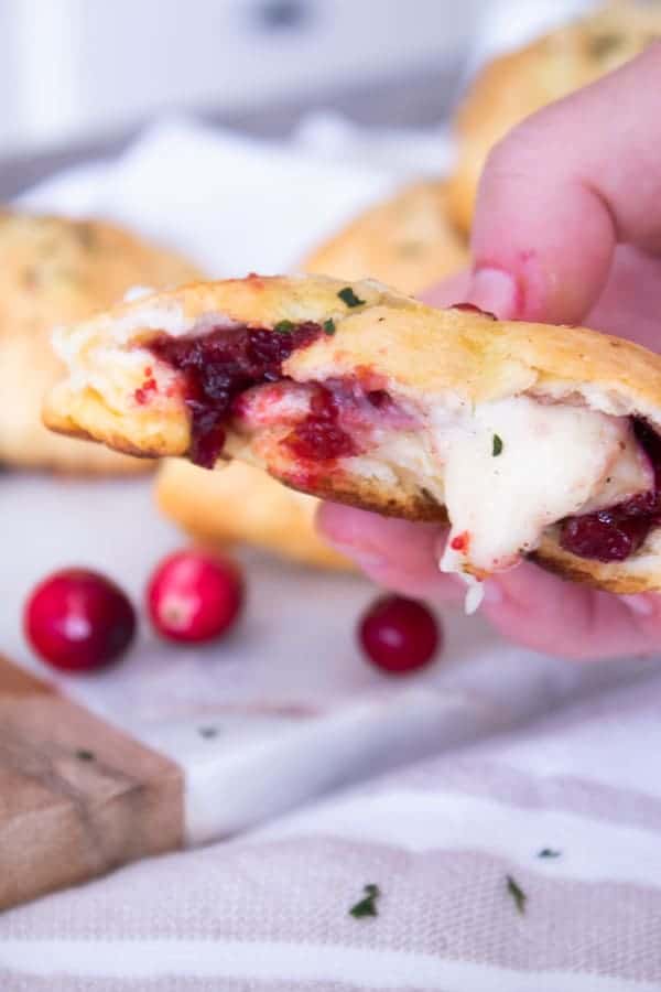 holding a cranberry brie biscuit bomb in half with melted brie