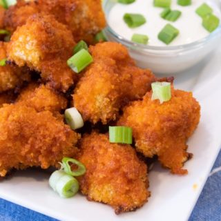 buffalo cauliflower bites on a white platter with celery and blue cheese