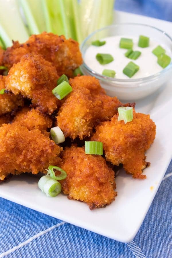 buffalo cauliflower bites on a white platter with celery and blue cheese