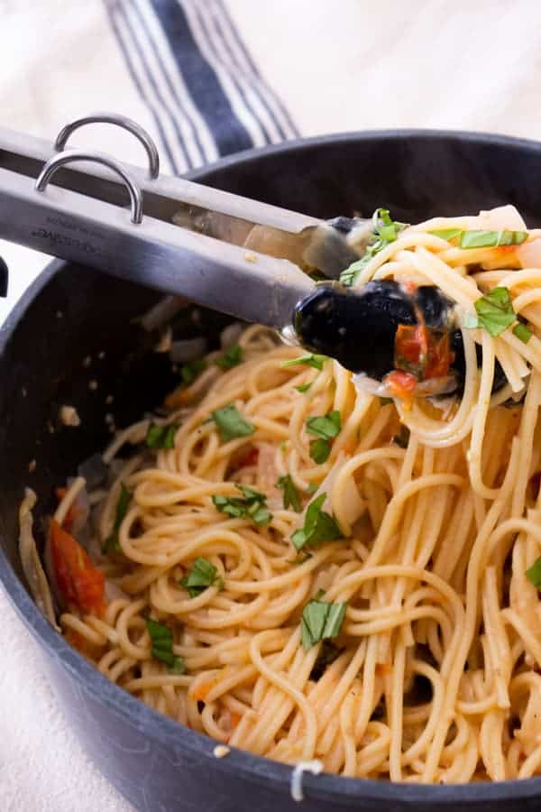 one pot pasta in a black pot garnished with basil