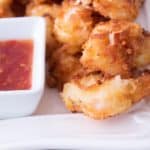 coconut shrimp on a white platter with Thai chili sauce