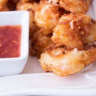 coconut shrimp on a white platter with Thai chili sauce