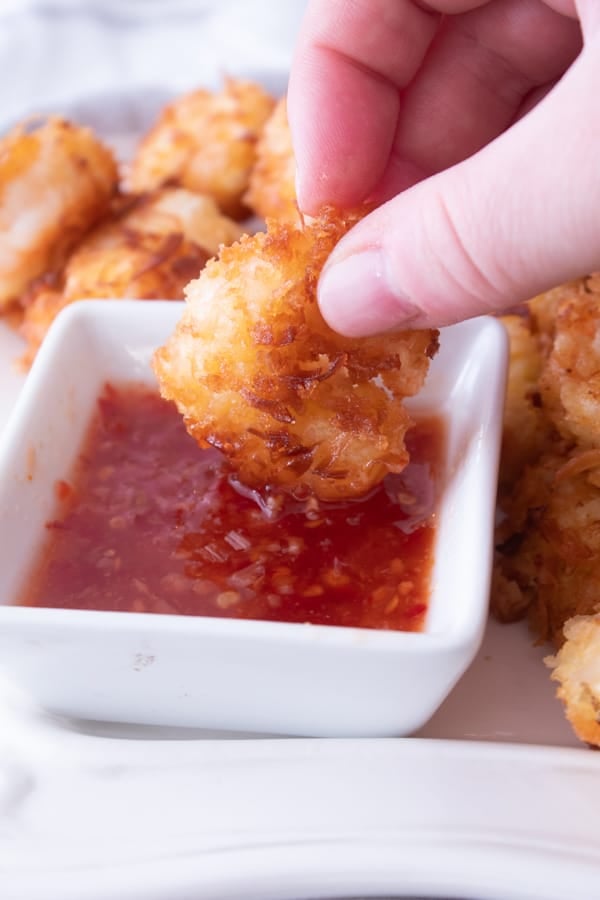 dipping coconut shrimp in thai chili sauce