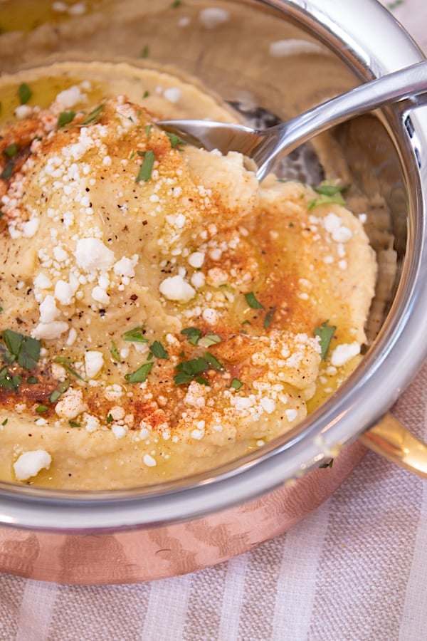 hummus being lifted on a silver spoon