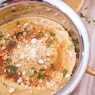 a copper dish full of no tahini hummus with feta olive oil and spices